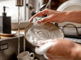 Girl washing dishes at kitchen at home