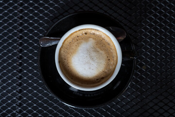 Taza de café con leche con espuma, plano cenital, fondo negro, taza negra
