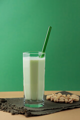 Pistachio milk in the glass on a dark green linen napkin. Lactose free pistachio milk and scattered pistachios. Copy space