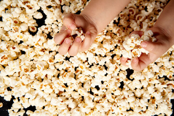 Children's hands are picking up popcorn. Flat lay . The concept of a birthday, party, holiday, home leisure. Copy space for your product. Popcorn texture or background.