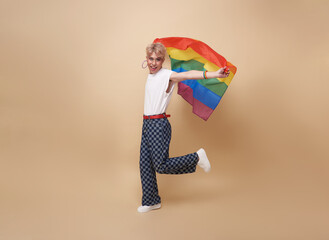 Youth asian transgender LGBT showing rainbow flag isolated on nude color background. gender expression pride and equality concept.