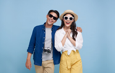 Excited Asian couple tourist dressed in summer clothes to travel on holidays isolated on blue...