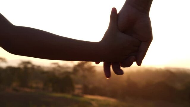 Concept of Mothers day, Happy Family. Close-up mother and child daughter hands joining, holding together with sunlight flare natural background, 4K. Romantic moment between mom and daughter