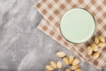 Fototapeta na wymiar Pistachio milk in a glass on a gray concrete background. Organic lactose free pistachio milk and pistachios. Top view. Copy space
