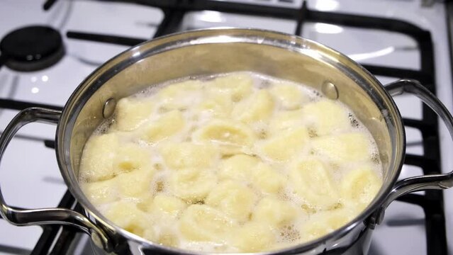 Lazy dumplings from curd dough are boiling in the pan. Top view. A traditional dish of Russian and Ukrainian cuisine. Tasty breakfast. Homemade food. Halushki.