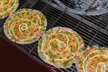 Grilled vietnamese pizza with eggs, sausages and sauces in vietnamese night market in Da Lat