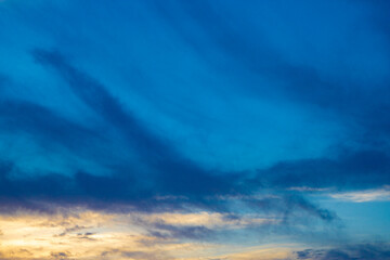 都会の空に広がる幻想的な青とオレンジの暗めのグラデーションの夕焼け空と黒い雲（東京都千代田区）