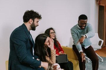 Multiracial colleagues burst out laughing after joking each other while taking a break at work
