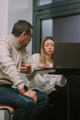 Middle-aged business manager warning his female colleague to stop chatting on her phone while working on the project with him