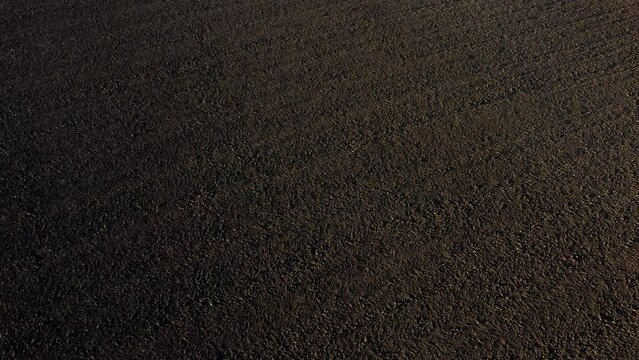 Landscape of plowed up land on an agricultural field on a sunny autumn day. Flying over the plowed earth with black soil. Black soil. Ground earth dirt priming aerial drone view. Agrarian background