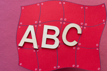 wood letters (abc) on red paper shape with grid