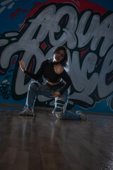 Female dancer in activewear squatting on the floor of modern dance studio and looking at you