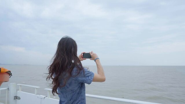 Young Latin man filming the Rio de la Plata as he travels along it on a ferry. 4k video.