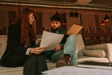 Handsome male business person trying to help his ginger female coworker after she asked for his help
