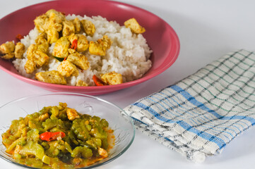 stir-fried bitter melon with sliced tempeh and white rice with sliced tofu cooked dry with chilies served in a small plate isolated on a white background