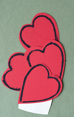 grungy red hearts with black outlines on rough green paper