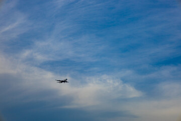 Fototapeta na wymiar 都会の空に広く大きく雄大に広がる青空と雲と、発着する夕方近くの飛行機（東京都大田区）