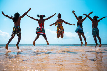 Kenyan people jump on the beach with typical local clothes