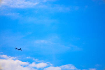 Fototapeta na wymiar 都会の空に広く大きく雄大に広がる青空と雲と、発着する夕方近くの飛行機（東京都大田区）