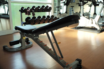 Fototapeta na wymiar Rear view of exercise bench with blurred racks of dumbbells in background