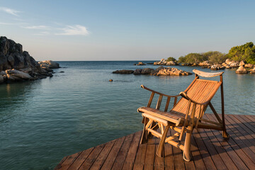 Fototapeta na wymiar Wooden sunbed at resort patio by sea in morning, Ko Man Klang