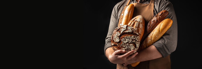 Man holding breas in his hands. Different types of bread. bakery products on a dark background....