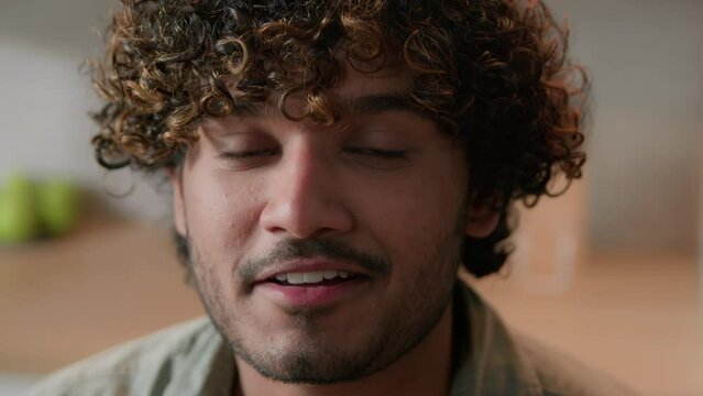 Close up smiling Arabian man homeowner with curly hair vlogger look at camera at kitchen. Portrait Indian male face with smile indoors. Headshot ethnic guy business video conference call web cam view
