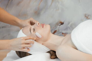 Obraz na płótnie Canvas facial peels at the salon skin care concept Close-up portrait of a woman using a quartz roller massager on her cheek for an alternative anti-aging. ery beautiful girl doing facial massage at the spa s