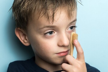 a small boy of Slavic appearance holds a bamboo toothbrush near his face. close-up portrait