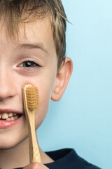 a small boy of Slavic appearance holds a bamboo toothbrush in his hands. close-up portrait