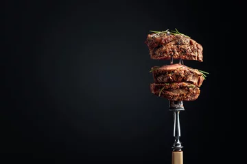 Poster Medium rare beef steak with rosemary on a black background. © Igor Normann