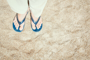 Fototapeta premium Beautiful legs in slippers on the sand background