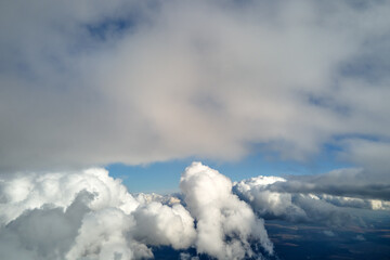 Aerial view from airplane window at high altitude of earth covered with puffy cumulus clouds...
