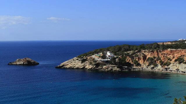 The iconic Cala Hort in the Balearic archipelago. Aerial view of the golden sand beach and the promontory which flows into a paradisiacal sea.