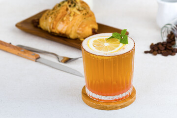 Iced orange with soda and mint leave on wood coaster and white background