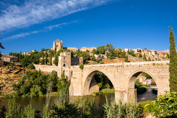 Obraz premium View of the San Martin Bridge crossing the Tagus to enter the old city of Toledo on the hill where you see the Old Cathedral