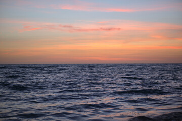 Dramatic red ocean waves at sunset with soft evening sea dark water