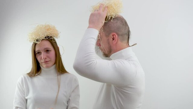 man and girl on white background pretend to be angels in their hands a box of packing materials on people's heads. interesting delivery Angel delivery unpacking. funny people head nest
