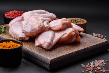 Raw chicken wings with salt, spices and herbs on a wooden cutting board