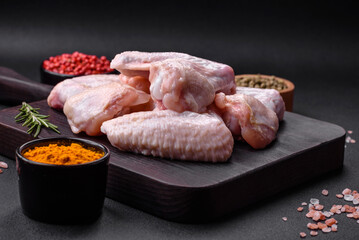 Raw chicken wings with salt, spices and herbs on a wooden cutting board