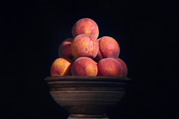 Red-yellow peaches on clay bowl on a rustic wooden table against dark background