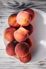 Red-yellow peaches on a plate on a rustic wooden table. Close-up, top view, vertical
