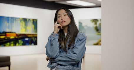 Portrait of 30s Asian female engaging with art at an exhibition. Modern fine arts museum. Model and property released