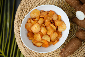 Indonesia Cassava chips in bowl and tapioca root. Popular hot spicy yuca chips. View from above.