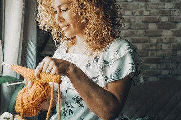 Smiling woman working with knitting rok hobby at home. Indoor leisure activity time. Adult female smile. Curly hair. Young mature lady people doink knit activity and enjoying time alone. Window light