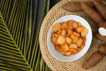 Indonesia Cassava chips in bowl and tapioca root. Popular hot spicy yuca chips. View from above.
