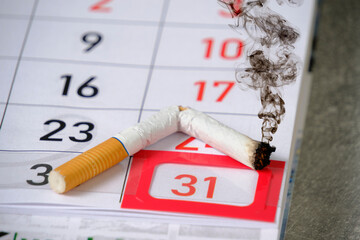 Black smoke coming from discarded cigarette.Background is calendar with 31st number marked.Concept...