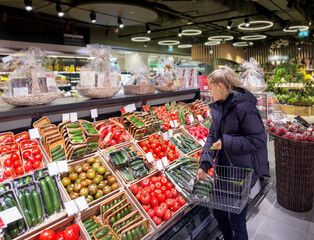 Woman buying vegetables(tomatoes and cucumbers) at the market