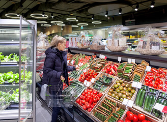 Woman buying vegetables(tomatoes and cucumbers) at the market