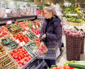 Woman buying vegetables(tomatoes and cucumbers) at the market